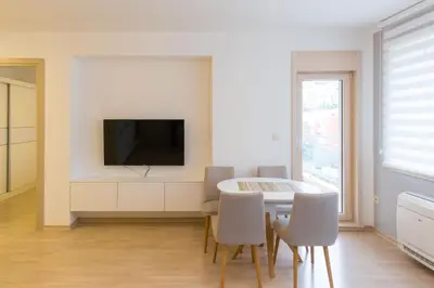 a dining room with a table and a tv on a wall at Central Budva apartment in Budva
