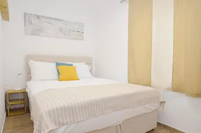 a bedroom with a white bed with a yellow pillow at DC Apartment C in Kotor