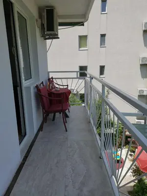 a balcony with a red chair and a table at Apartments Nikčević in Budva