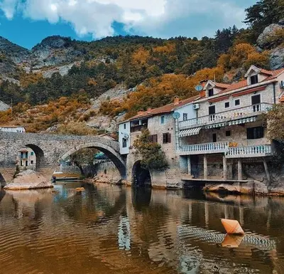 a bridge over a body of water with buildings and a river at Milovan in Cetinje