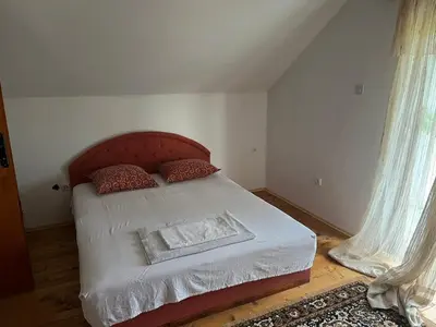 a bedroom with a bed with a red headboard and curtains at Milovan in Cetinje