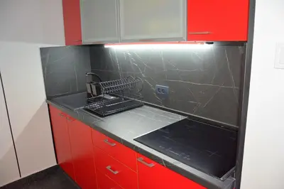 a red kitchen with a sink and red cabinets at Montenegro Backpackers Home Budva in Budva