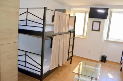 a room with two bunk beds and a glass table at Montenegro Backpackers Home Budva in Budva