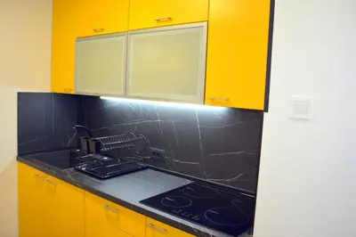 a kitchen with yellow cabinets and a black counter top at Montenegro Backpackers Home Budva in Budva