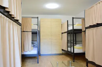 a room with three bunk beds and a room with curtains at Montenegro Backpackers Home Budva in Budva