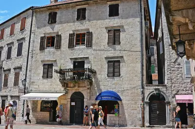 a large stone building with people walking in front of it at Montenegro Backpackers Home Kotor in Kotor