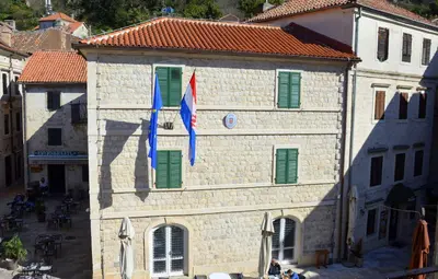 a building with green shutters and two flags on it at Montenegro Backpackers Home Kotor in Kotor