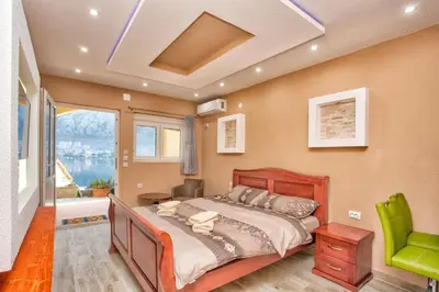 a bedroom with a bed and a green chair at Apartments Bella Vista in Kotor