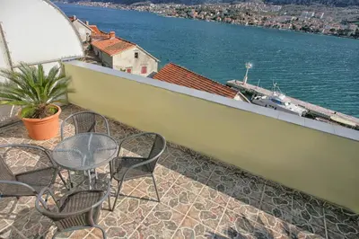 a balcony with chairs and tables and a view of the water at Apartments Bella Vista in Kotor
