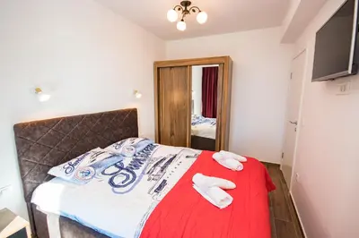 a bedroom with a bed with a red blanket and a mirror at Celebrity Style Lux Apartment in Bar