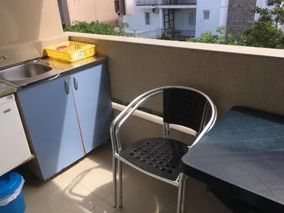 a chair in a kitchen with a sink and a table at Apartmani Vuković in Sutomore