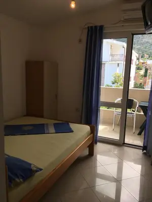 a bedroom with a bed and a balcony with a view at Apartmani Vuković in Sutomore