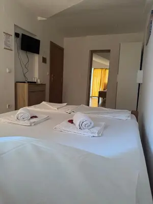 two white beds in a room with towels on them at Guesthouse Vila Tamburic in Becici