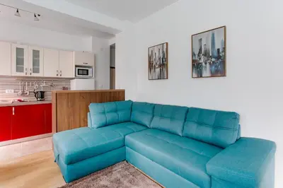 a blue couch in a living room with a kitchen at Apartments LORA 13.Jula, 15 in Budva