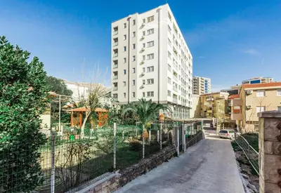 a tall white building in the middle of a city at Apartments LORA 13.Jula, 15 in Budva