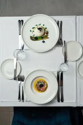 a white table with two plates and silverware on it at Hotel California by Aycon in Sveti Stefan