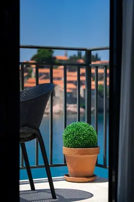 a chair and a potted plant on a balcony at Hotel California by Aycon in Sveti Stefan