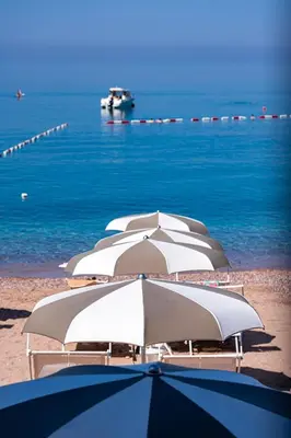 a row of white umbrellas on a beach at Hotel California by Aycon in Sveti Stefan