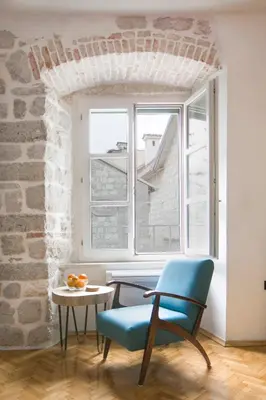 a blue chair in a room with a window at P.S. Cattaro Apartments in Kotor