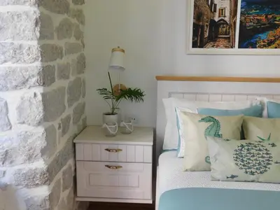 a bedroom with a bed with pillows and a night stand at P.S. Cattaro Apartments in Kotor