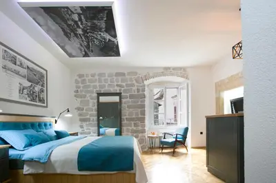 a bedroom with a bed and a stone wall at P.S. Cattaro Apartments in Kotor