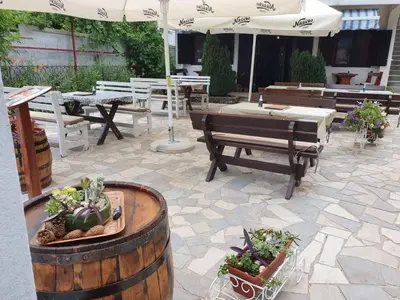 a patio with tables and benches and a table with an umbrella at Porto Njeguši A1 in Cetinje