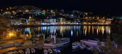 a city at night with boats in the water at Long Beach Apartment in Ulcinj