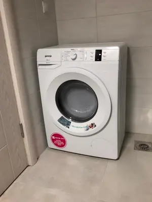 a white washing machine in a corner of a room at Long Beach Apartment in Ulcinj