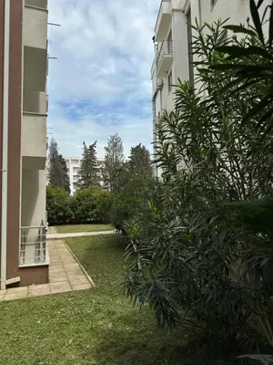 a building with a yard with a bush in front of it at Long Beach Apartment in Ulcinj