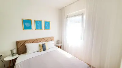 a bedroom with a bed with white sheets and a window at Olav Holiday Apartments Bar in Bar