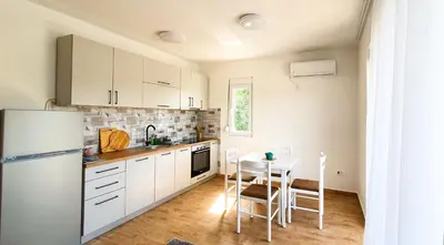 a kitchen with a table and a white refrigerator at Olav Holiday Apartments Bar in Bar