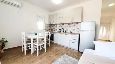 a kitchen with a table and a white refrigerator at Olav Holiday Apartments Bar in Bar