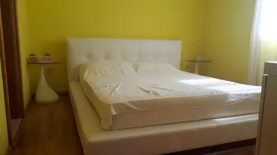 a white bed in a room with a yellow wall at BH Rialto in Sveti Stefan