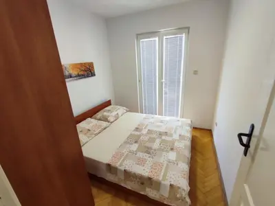 a small bedroom with a bed and a window at Apartman Milica in Budva