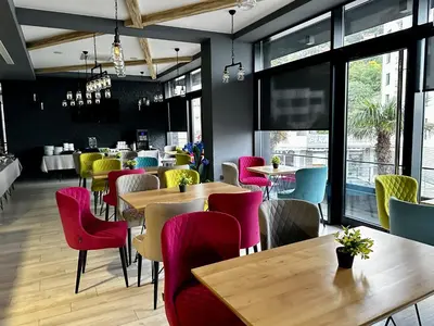 a restaurant with tables and chairs and windows at Hotel Del Medio in Sutomore