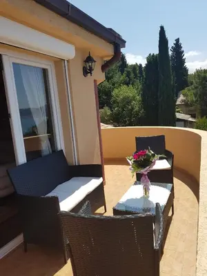 a table and chairs on a patio with a vase of flowers at Villa Jupok in Bar