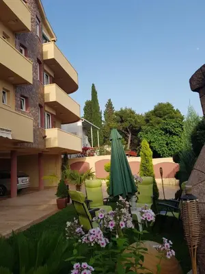 a patio with chairs and a green umbrella and flowers at Villa Jupok in Bar