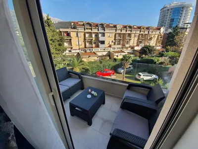 a balcony with chairs and a table and a view of a building at AS Apartments Budva in Budva