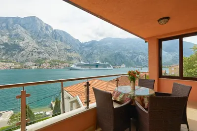 a balcony with a table and chairs and a boat in the water at Blanka Sea View Apartments in Kotor