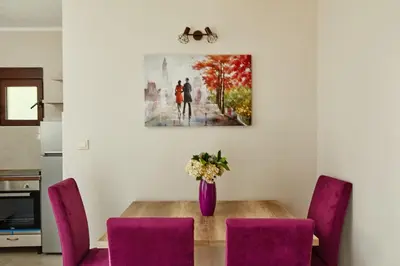 a dining room table with purple chairs and a vase with flowers at Blanka Sea View Apartments in Kotor