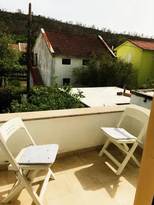 two chairs sitting on a balcony with a house at Vila Jovana in Sutomore
