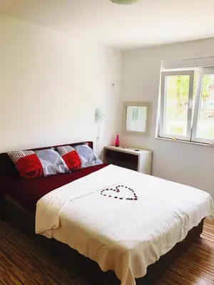 a bedroom with a large white bed with red pillows at Vila Jovana in Sutomore