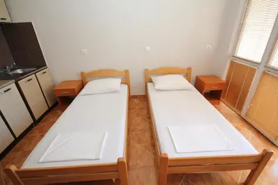 two beds in a small room with a kitchen at Apartments DEA in Bar