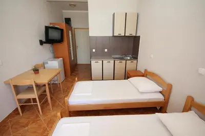 a room with two beds and a table and a kitchen at Apartments DEA in Bar