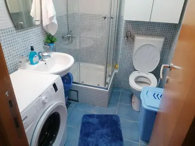 a bathroom with a toilet and a sink and a washing machine at Ksenija apartment in Budva