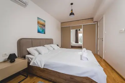 a bedroom with a large bed with white sheets at Blue Marlin Apartments in Budva