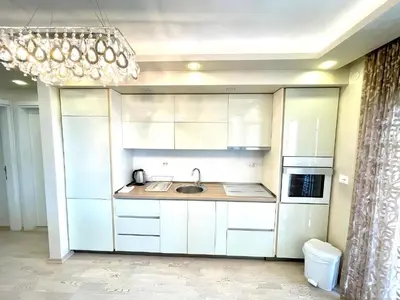 a kitchen with white cabinets and a sink and a chandelier at Blue Marlin Apartments in Budva