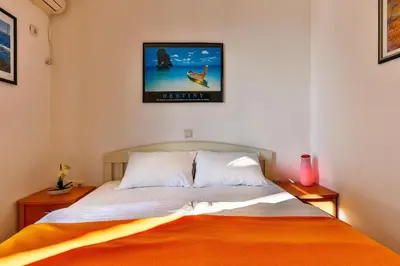a bedroom with a bed with an orange blanket at Apartmani Luka - Vila Brzulovic in Rafailovici