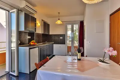 a kitchen with a table with a bottle of wine at Apartmani Luka - Vila Brzulovic in Rafailovici