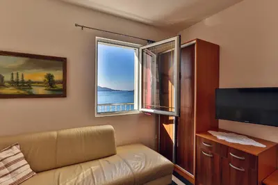 a living room with a couch and a window at Apartmani Luka - Vila Brzulovic in Rafailovici